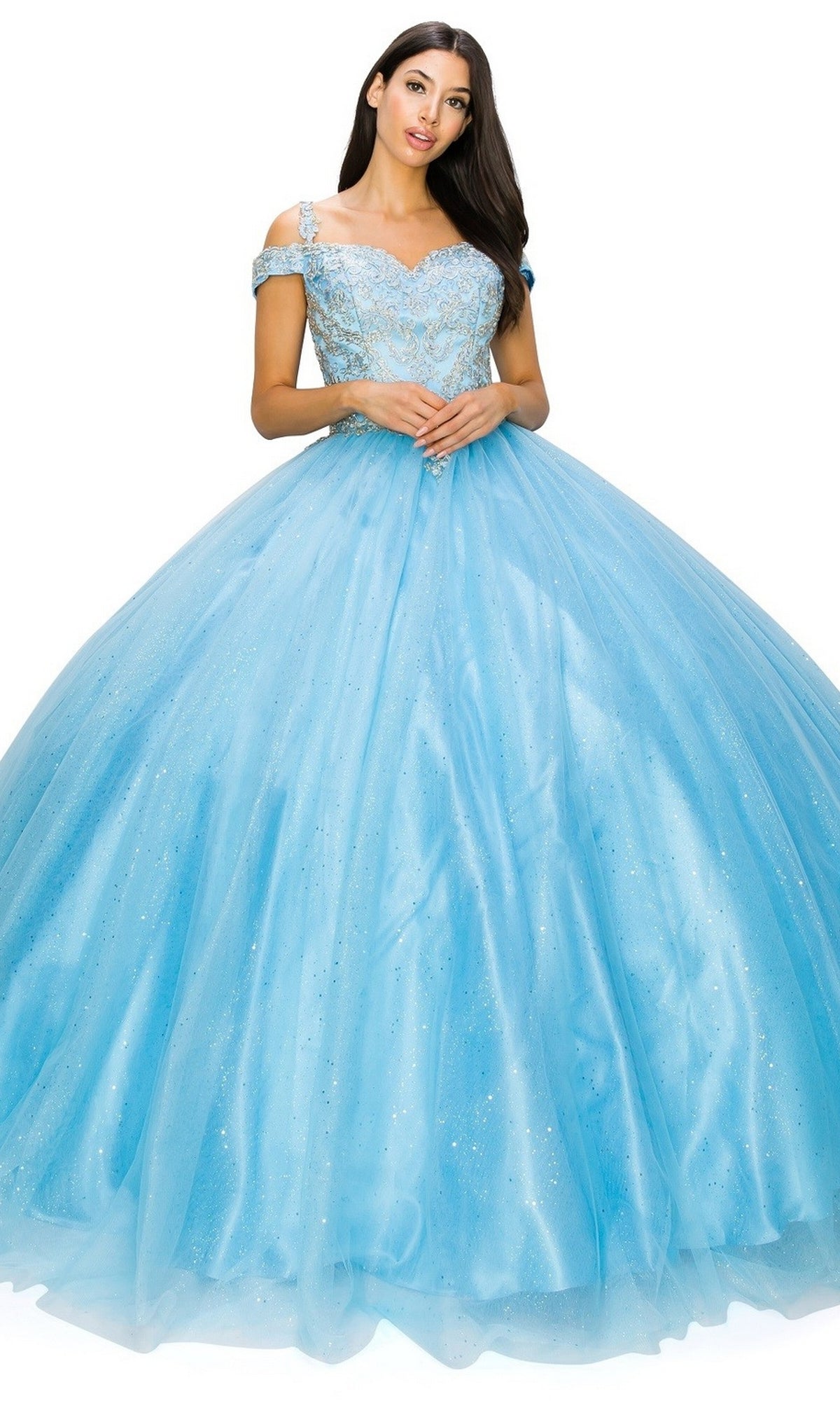 A woman wearing the Quinceanera Ball Gown 8028J, featuring a light blue off-the-shoulder design with a glitter tulle ball gown skirt and intricately embroidered bodice, stands against a white background.